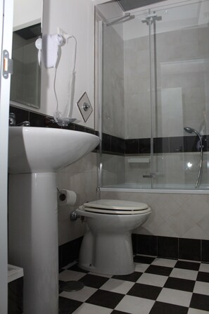 A bathroom with a white sink, toilet, and a glass-enclosed shower. - Residenza Nicola Amore (Naples)