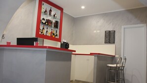 A bar area with a red counter, shelves with bottles, and a menu board. - Residenza Nicola Amore (Naples)