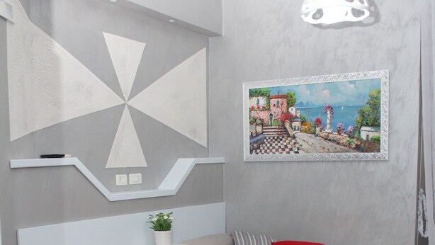 A modern bedroom with a bed, pillows, a bedside table with a plant, and a wall-mounted artwork. - Residenza Nicola Amore (Naples)