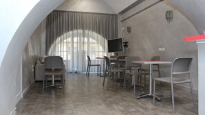 A modern conference room with a curved ceiling, grey chairs, a large table, and a television. - Residenza Nicola Amore (Naples)