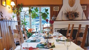 Een eettafel gedekt met verschillende gerechten, waaronder koekjes en brood, in een kamer met houten stoelen en uitzicht op de omgeving.