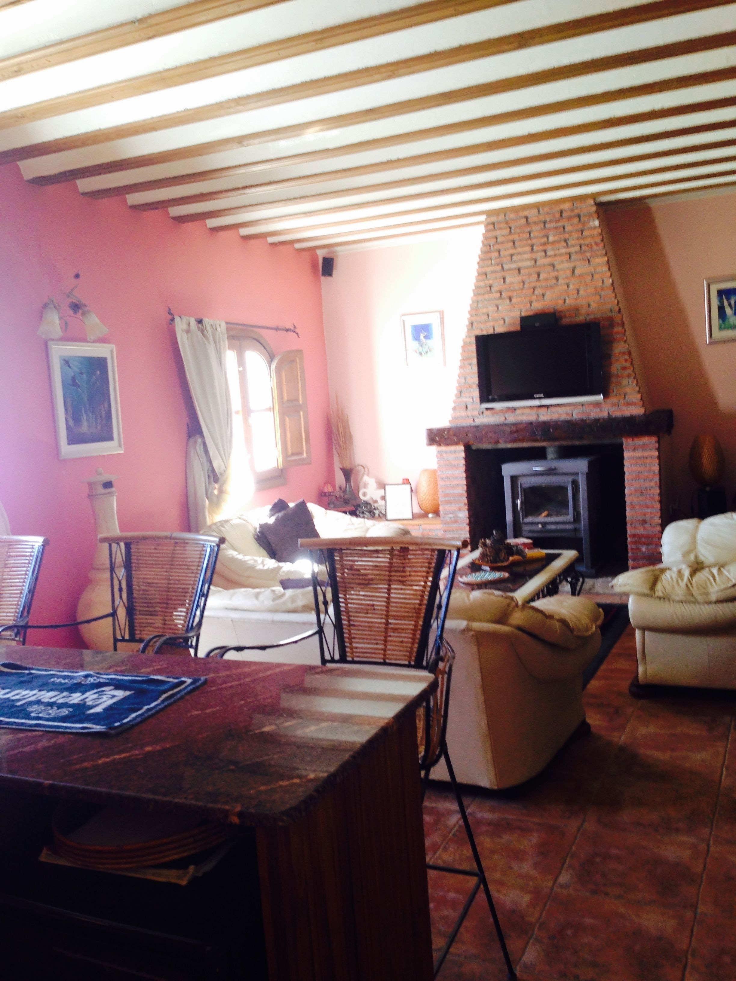 A cozy living room with a brick fireplace, a television mounted above it, and a dining area with a table and chairs.