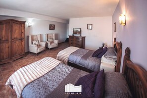 Ein Hotelzimmer mit zwei Betten, einem Kleiderschrank, einem Schminktisch und zwei Sesseln.