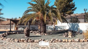 A courtyard with a stone floor, palm trees, a Buddha statue, and a pagoda. - Hotel Los Sibileys (Lorca)