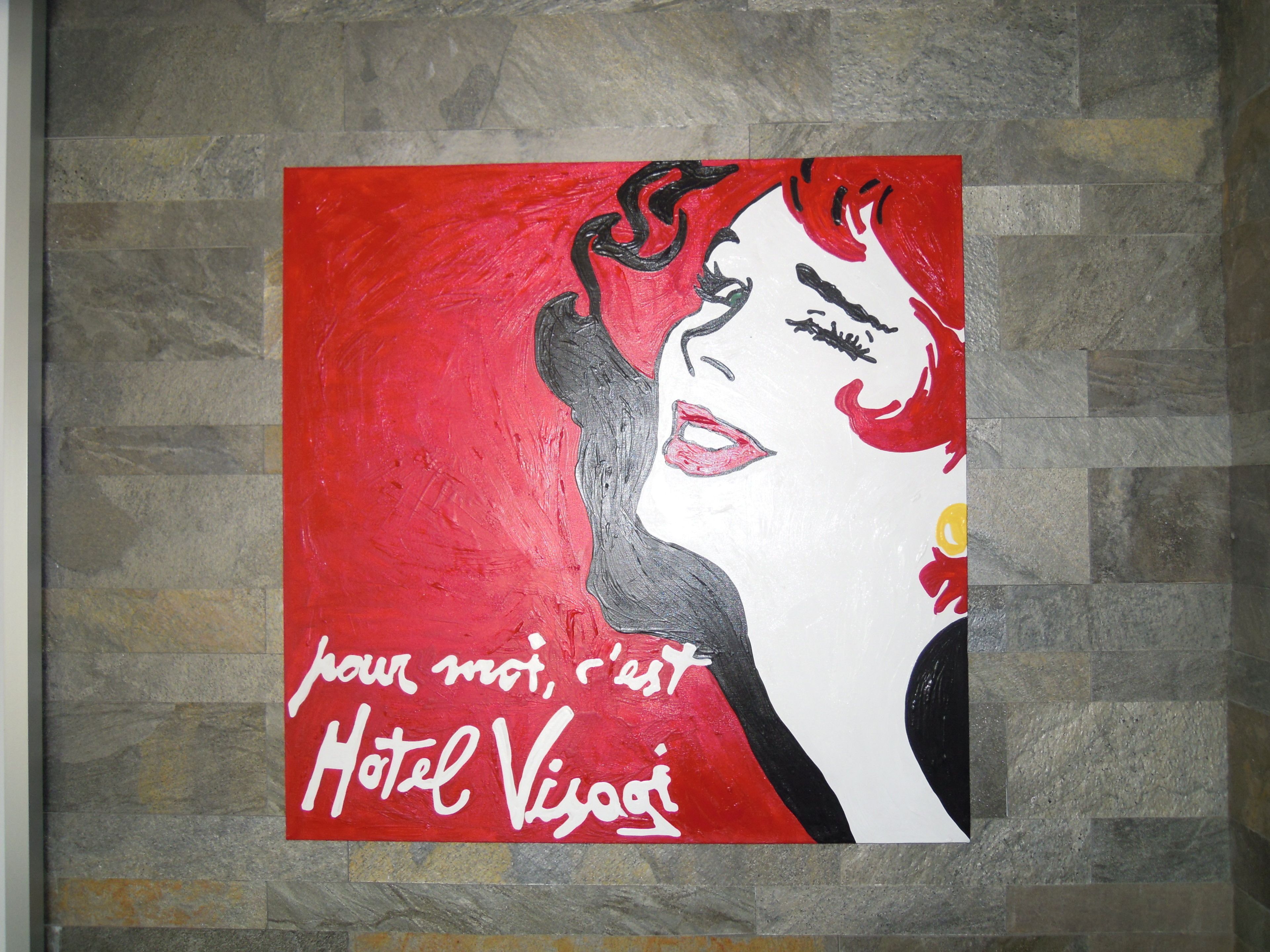A wall with a red and white painting of a woman and the text "pour moi, c'est Hotel Vivez".