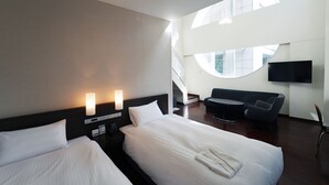 A hotel room with two beds, a sofa, a TV, and a staircase leading to an upper level. - KOKO HOTEL Sendai Kotodai Park (Sendai)