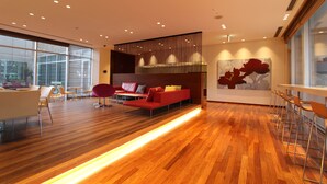 A modern interior with a wooden floor, a red sofa, and a bar area with stools. - KOKO HOTEL Sendai Kotodai Park (Sendai)