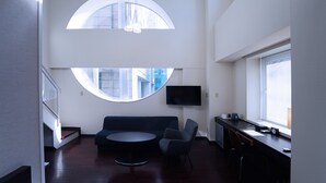 A modern room with a round table, a sofa, and a TV mounted on the wall. - KOKO HOTEL Sendai Kotodai Park (Sendai)