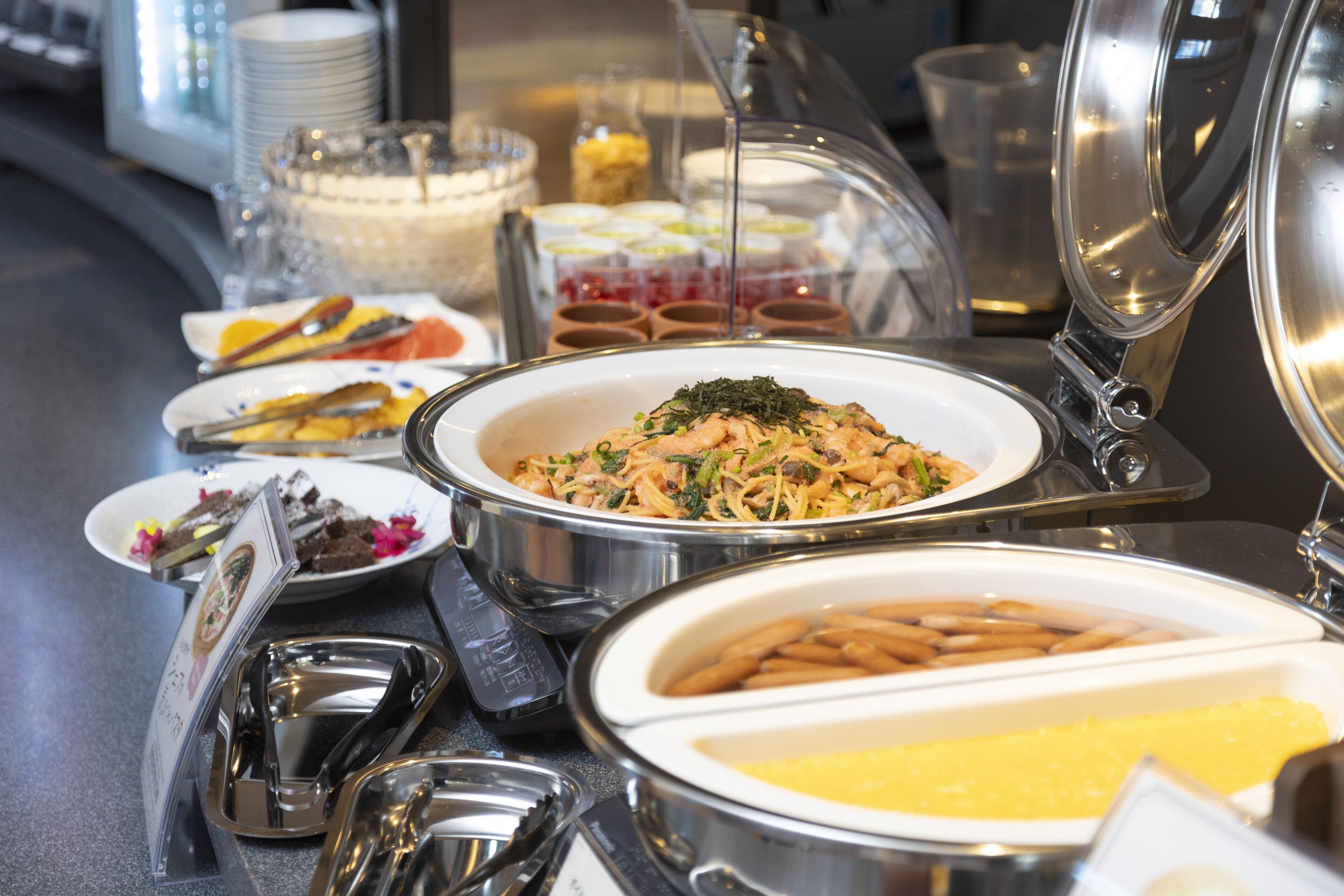 Un buffet proposant divers plats, notamment des pâtes, une salade et un plat de fruits de mer.