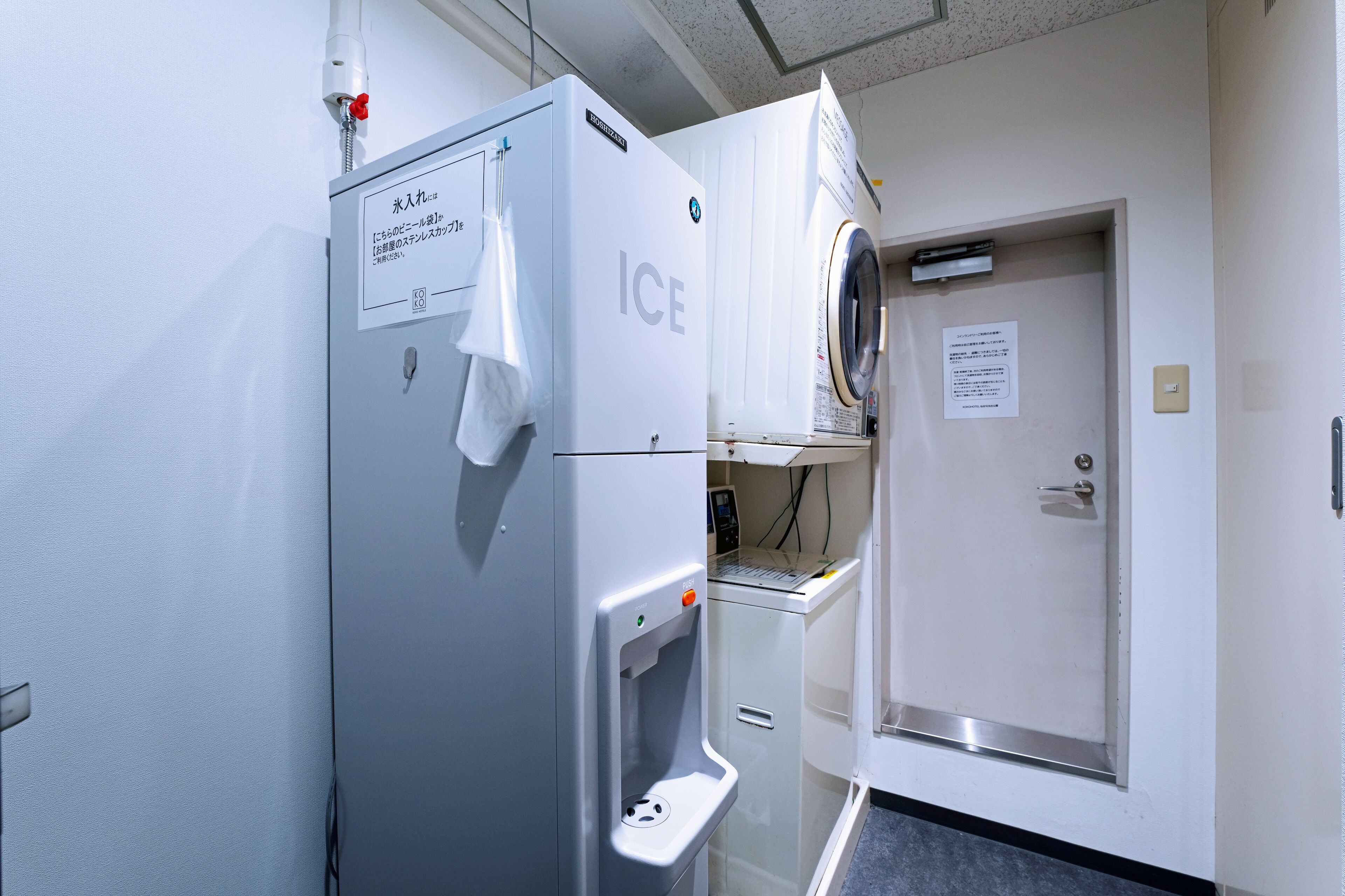 A hotel room with a white refrigerator, a water dispenser, and a washing machine.
