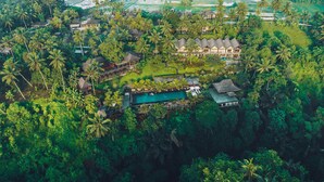 Vista aérea de un resort con varias construcciones, piscina y abundante vegetación.