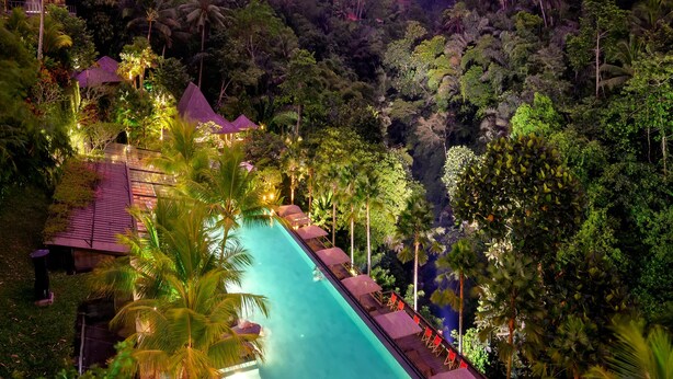 Un resort con piscina, sillones de descanso y un entorno tropical exuberante.