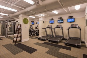 A gym with treadmills, exercise bikes, and a mirror.