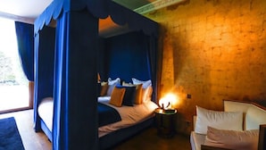 Un dormitorio con cama con dosel, una mesita de noche con lámpara y vistas al exterior.