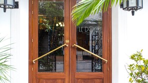 Una puerta doble de madera con un tirador de latón y una barra para jalar, que refleja un edificio con un letrero que dice "LE DOCTE CASABLANCA".