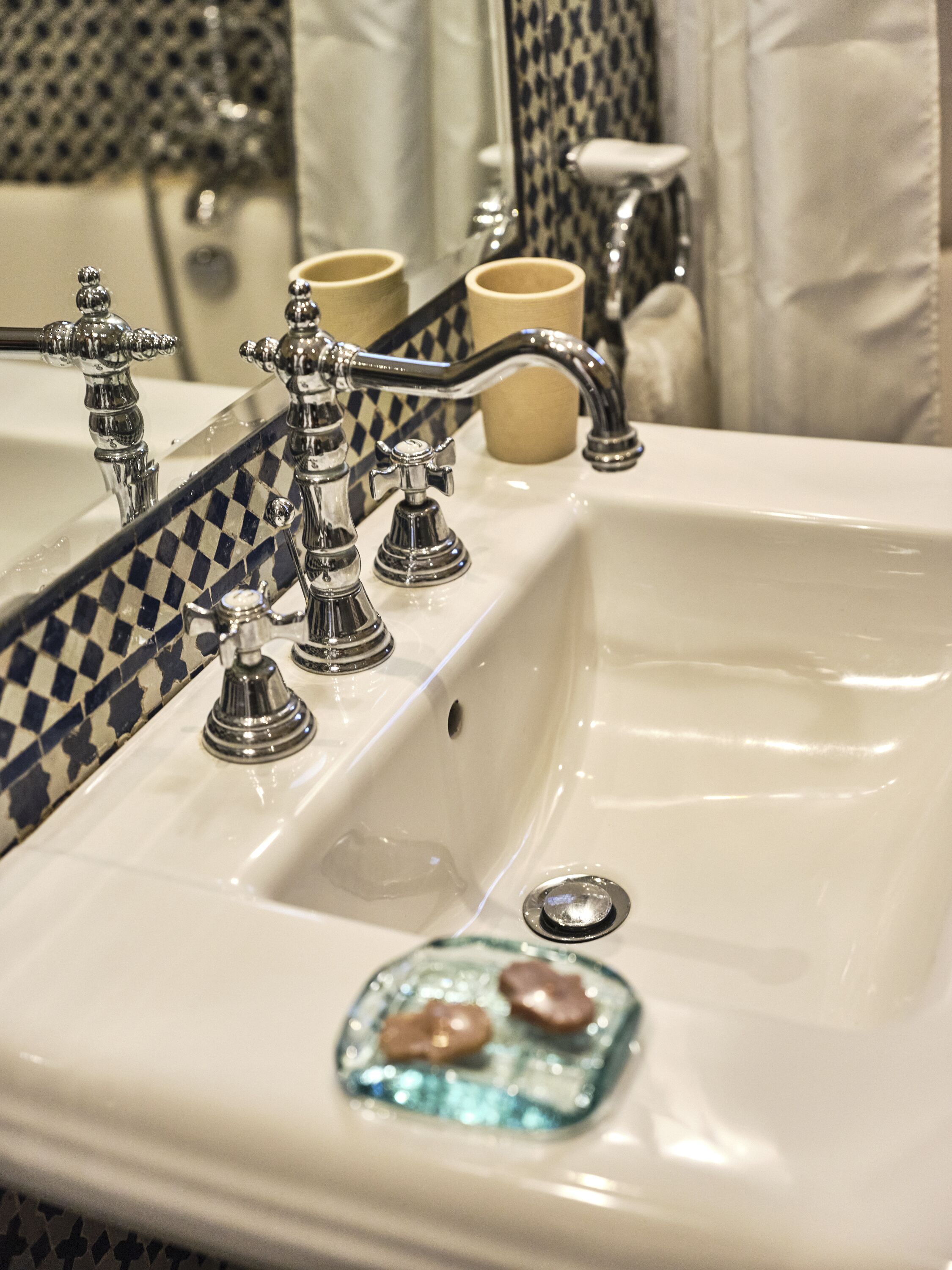 A bathroom sink with a mirror, chrome faucets, and a glass soap dish.