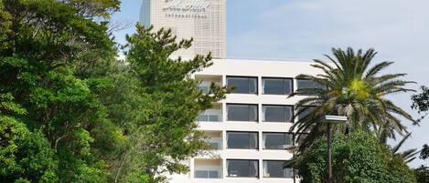 A modern hotel building with a prominent tower and a sign reading "John Hotel International".