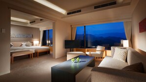 A hotel room with a bed, a sofa, a coffee table, and a TV. - Toba Hotel International (Toba)
