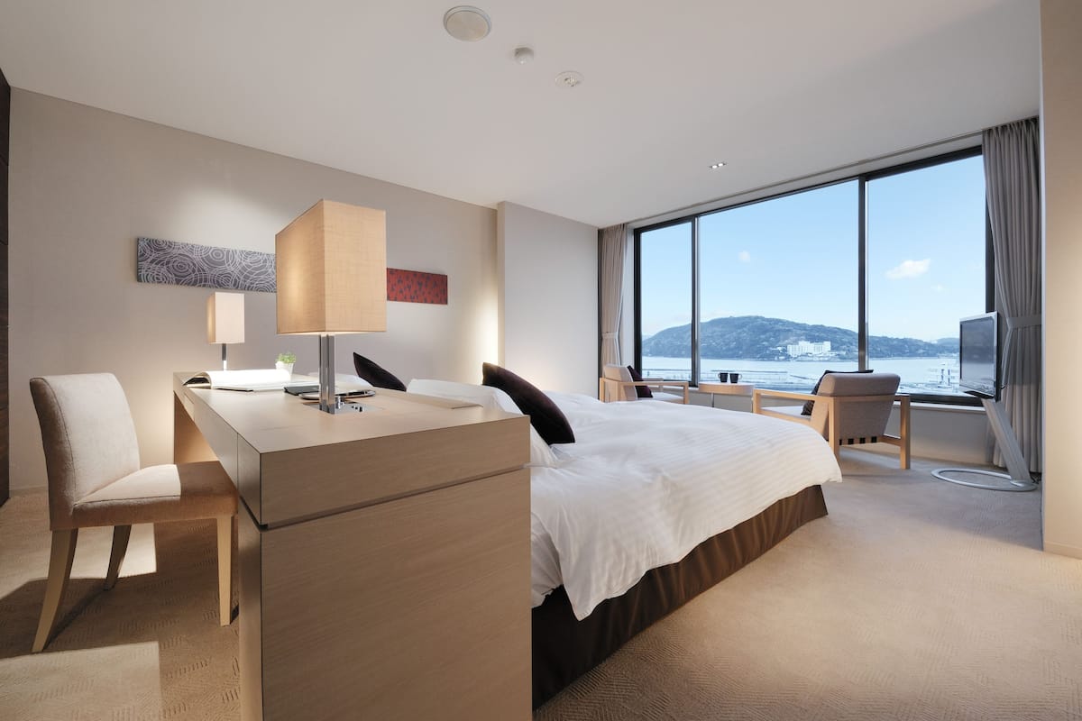 Una habitación de hotel moderna con una cama grande, un escritorio, una silla y vistas al mar.