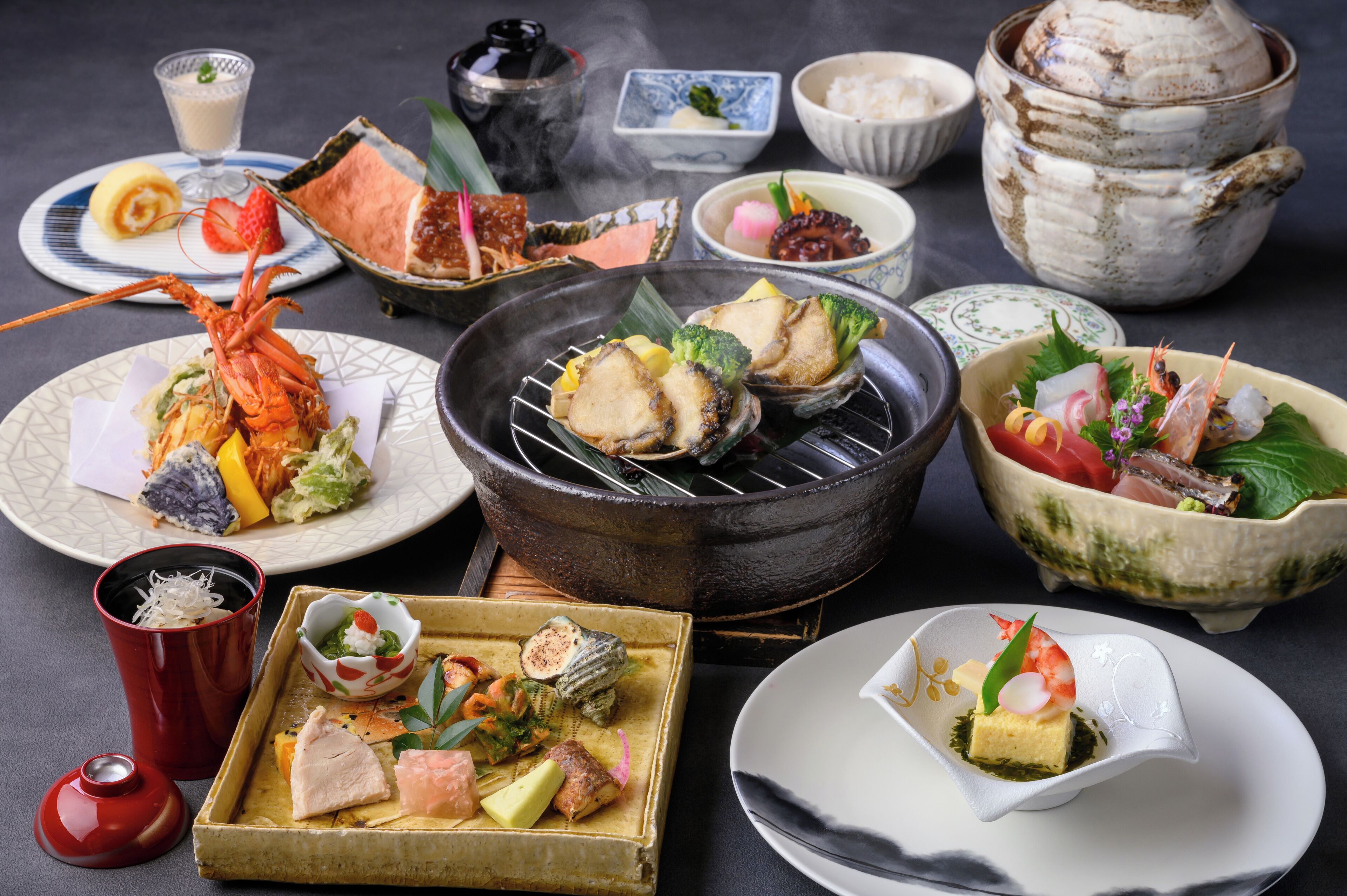 Une variété de plats japonais, notamment des fruits de mer, des légumes et du riz, servis dans de la vaisselle traditionnelle en céramique et en verre.
