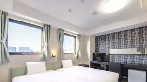Habitación de hotel con dos camas, un escritorio y una televisión, con vistas a la ciudad.
