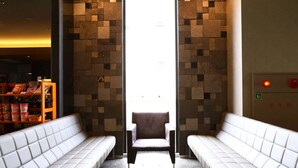 Un interior moderno con dos zonas de estar blancas con cojines, frente a una pared con un diseño geométrico de azulejos.