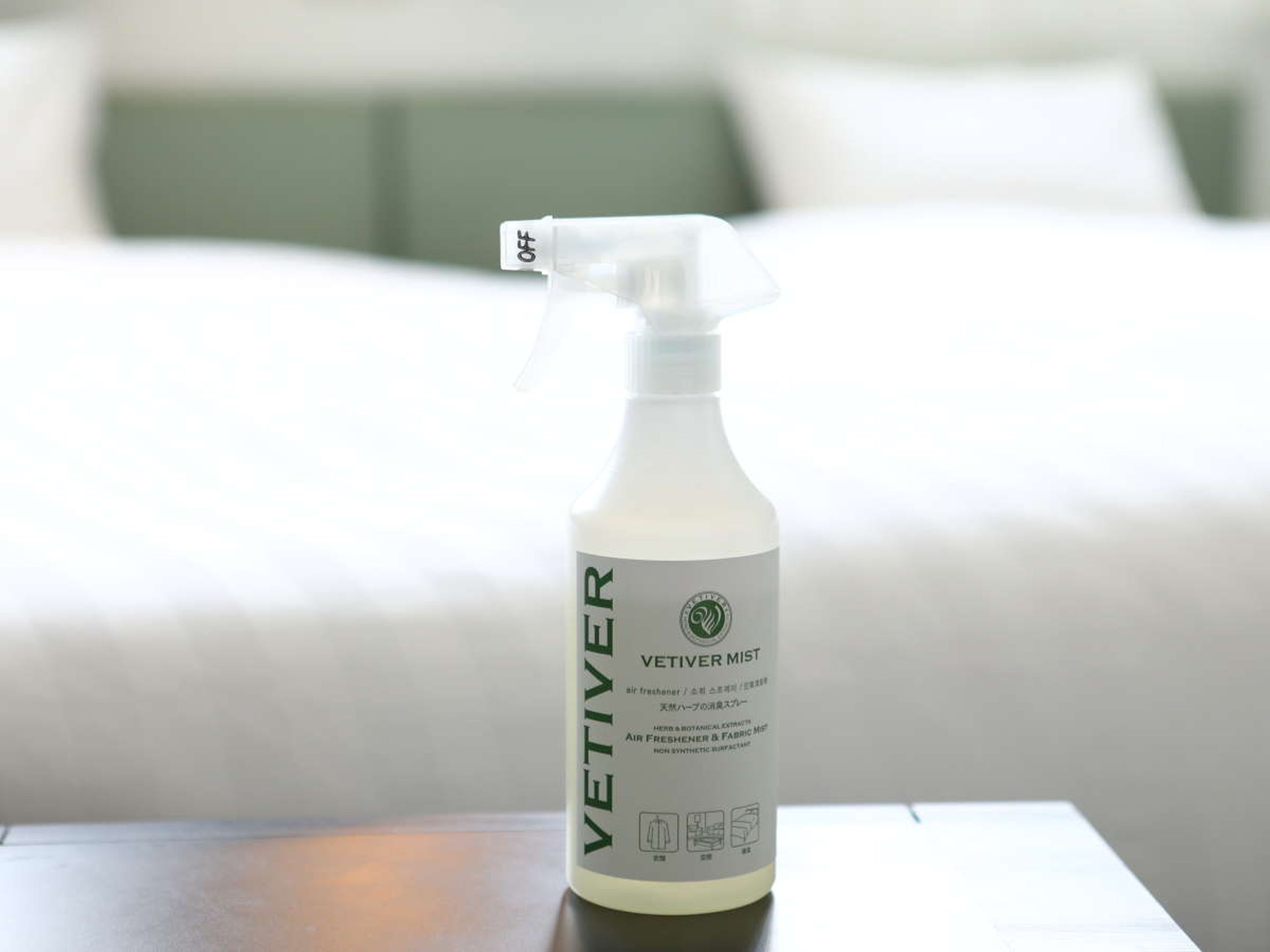 A bottle of VETIVER MIST on a table with a bed in the background.
