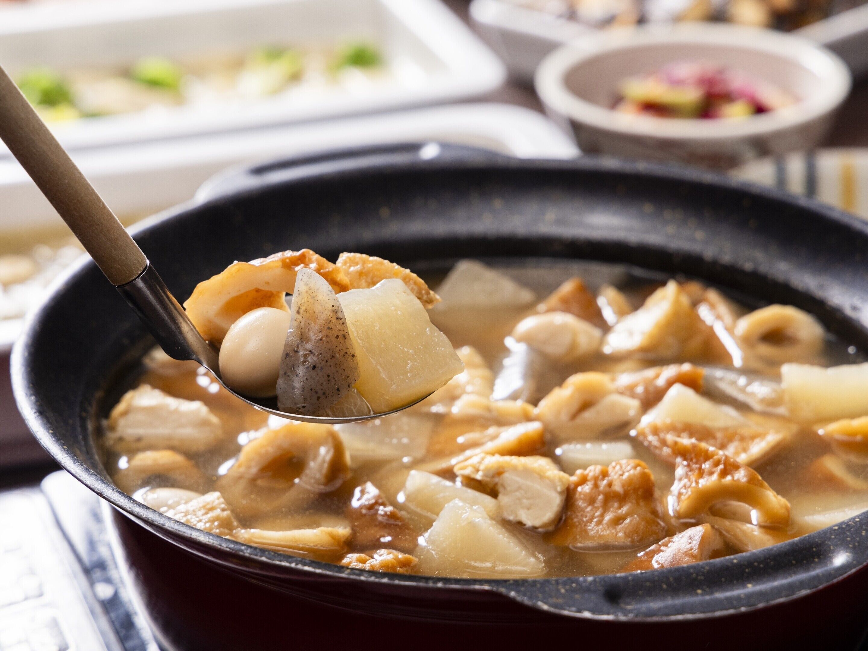 A close-up of a traditional Japanese dish being served in a black bowl.