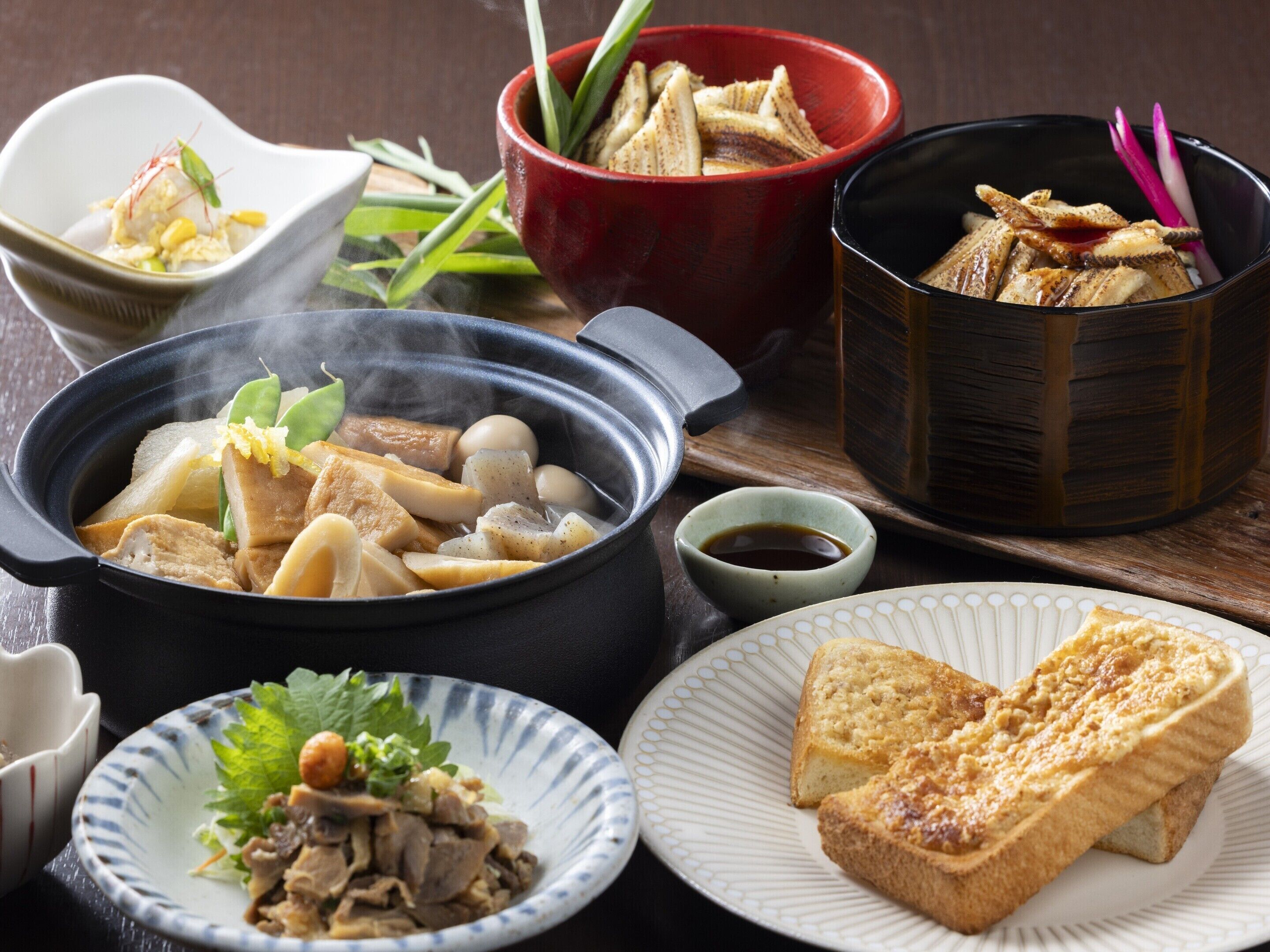 A variety of dishes, including a hot pot, sashimi, and bread, suggesting a dining experience.