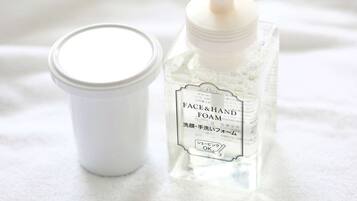 A bottle of face and hand foam with a pump dispenser and a small container with a lid.