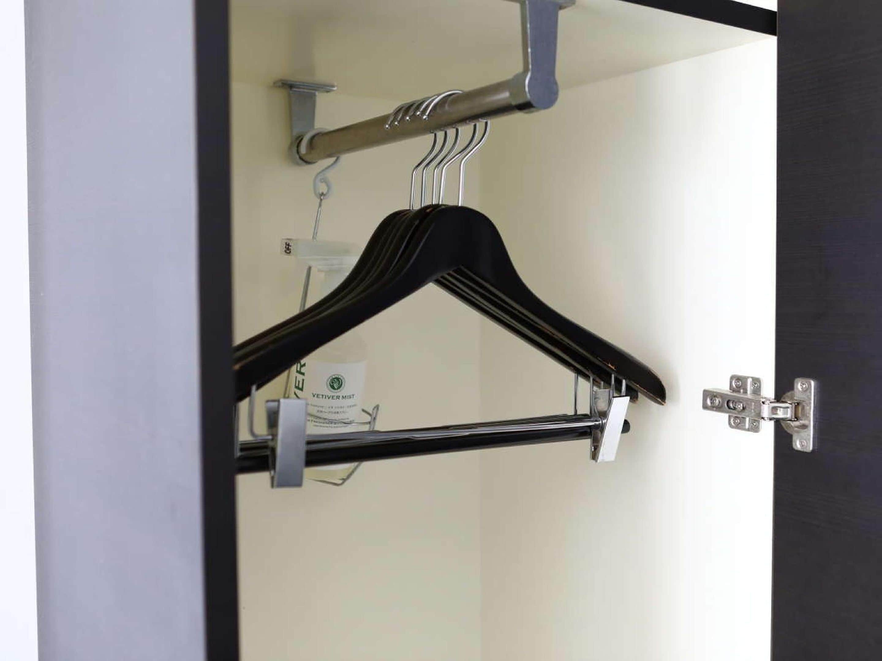 A room with a coat rack, a door with a silver handle, and a visible light switch.