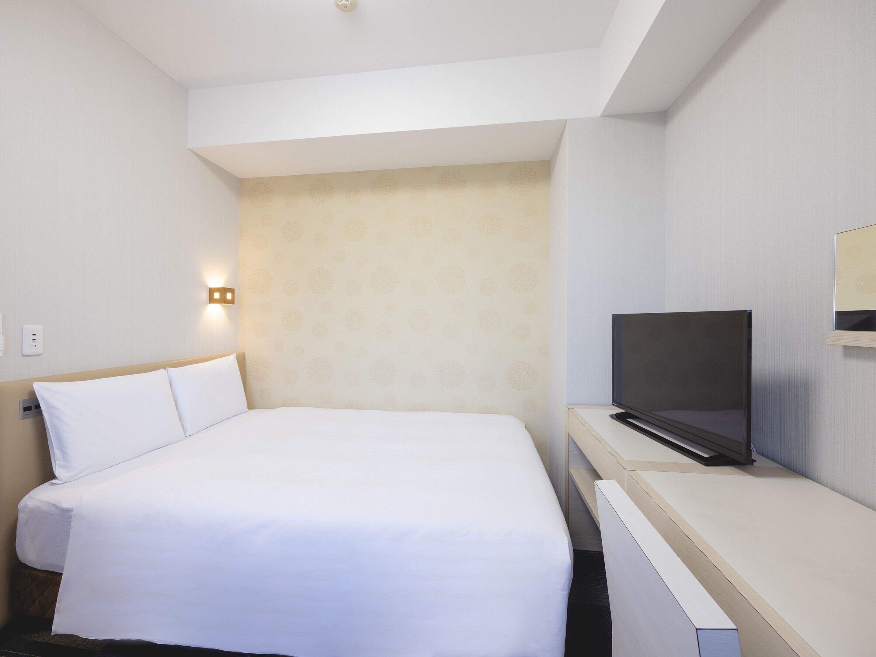 Una habitación de hotel con una cama grande, un televisor de pantalla plana y un escritorio pequeño.
