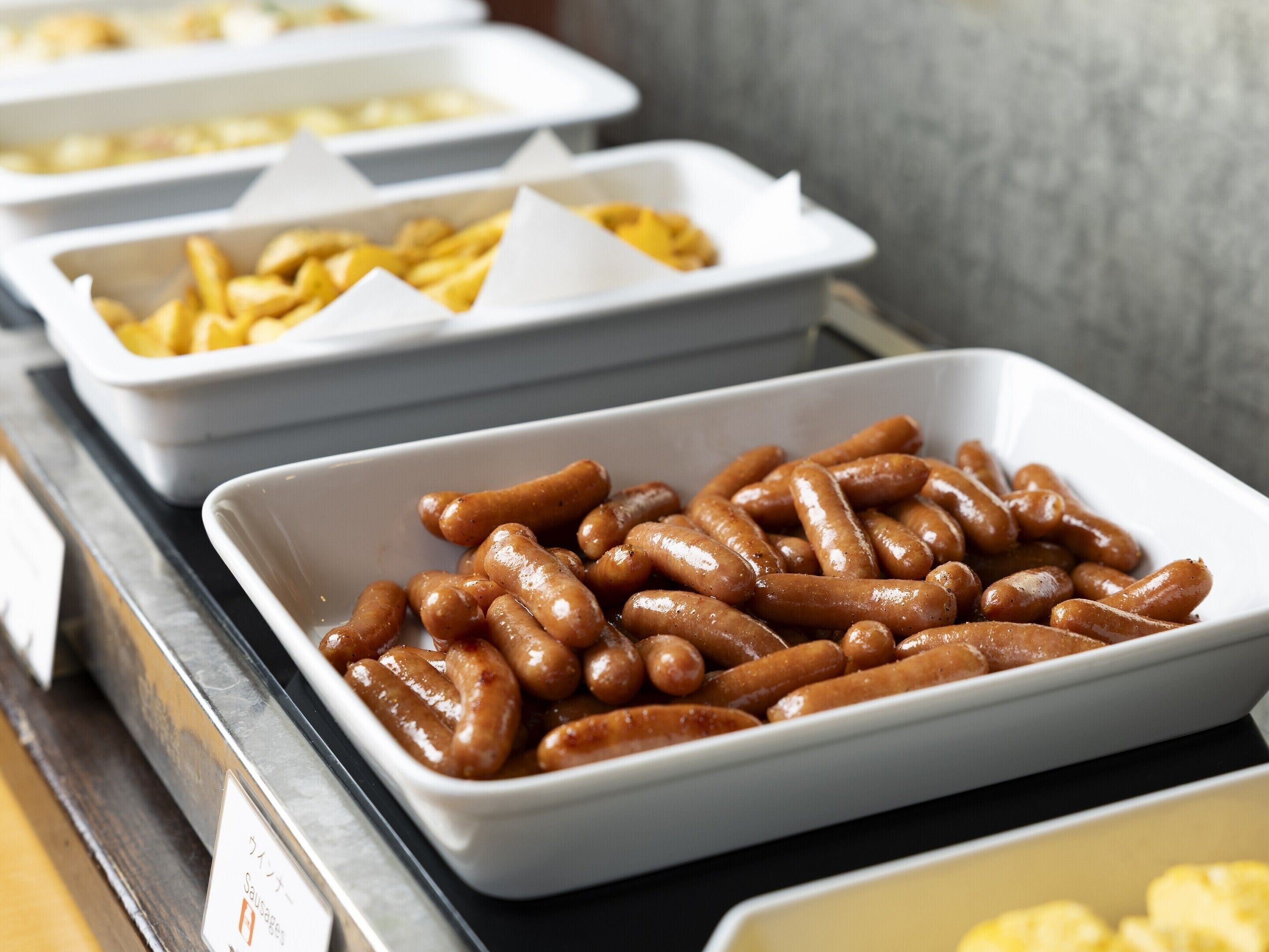 A buffet with various food items including sausages and fries.