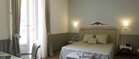 A hotel room with a large bed, bedside tables, a desk, and a chair.