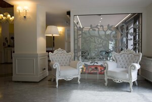 Una habitación con dos sillones blancos tapizados, un separador de vidrio decorativo y una lámpara.