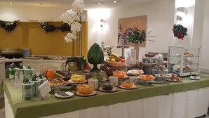 Montaje de bufé con diferentes alimentos, un mantel verde y una orquídea blanca decorativa.