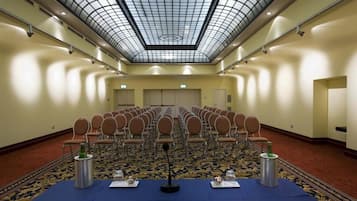 Ein Konferenzraum mit Stuhlreihen, einem Tisch mit Mikrofonen und einem gemusterten Teppich.