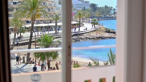 Vista costera con un paseo marítimo, palmeras y un litoral rocoso.