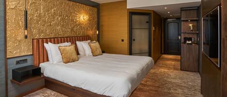 A modern bedroom with a large bed, a nightstand, a wall-mounted light, and a wooden wardrobe.