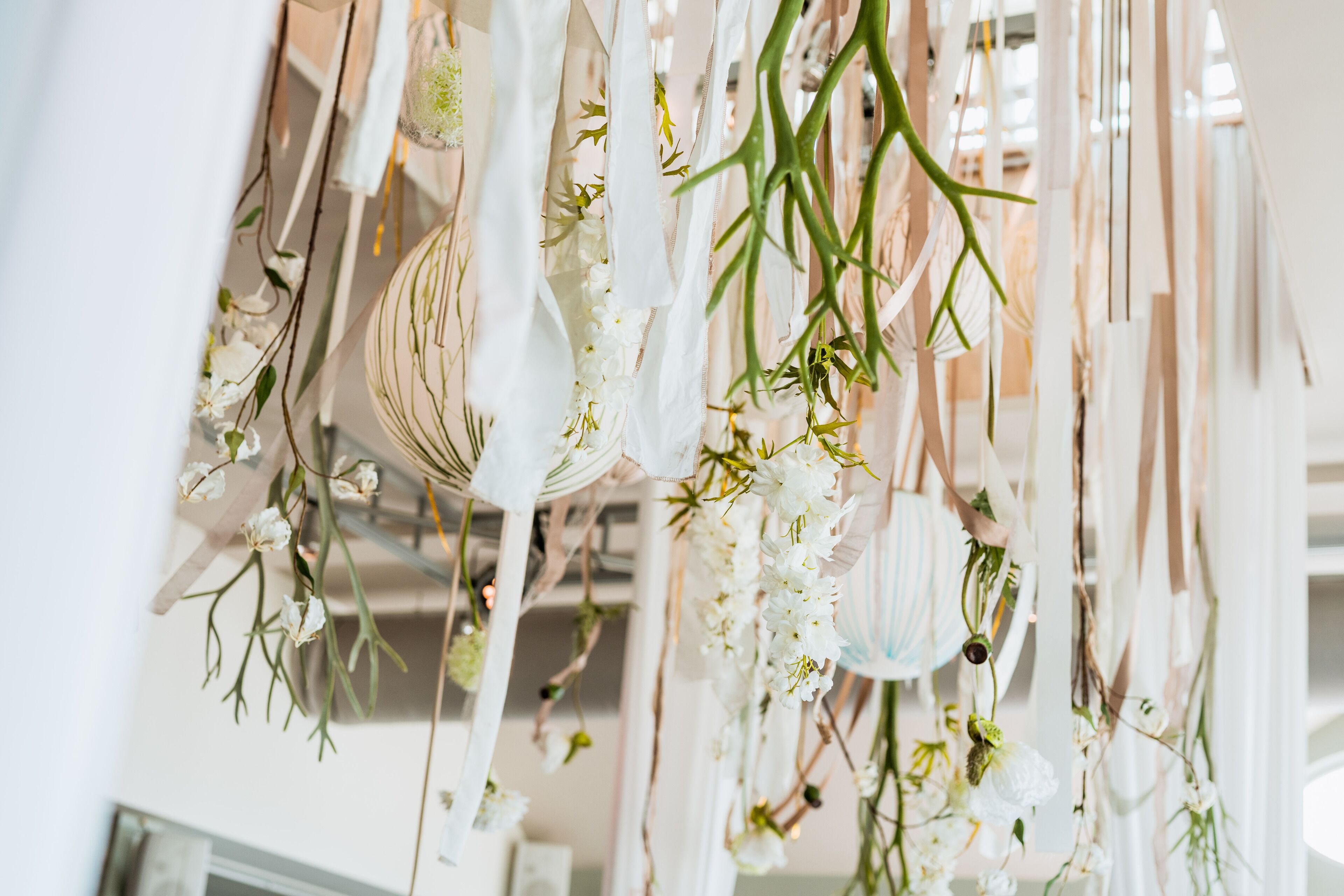 A room with hanging floral arrangements and a white wall.