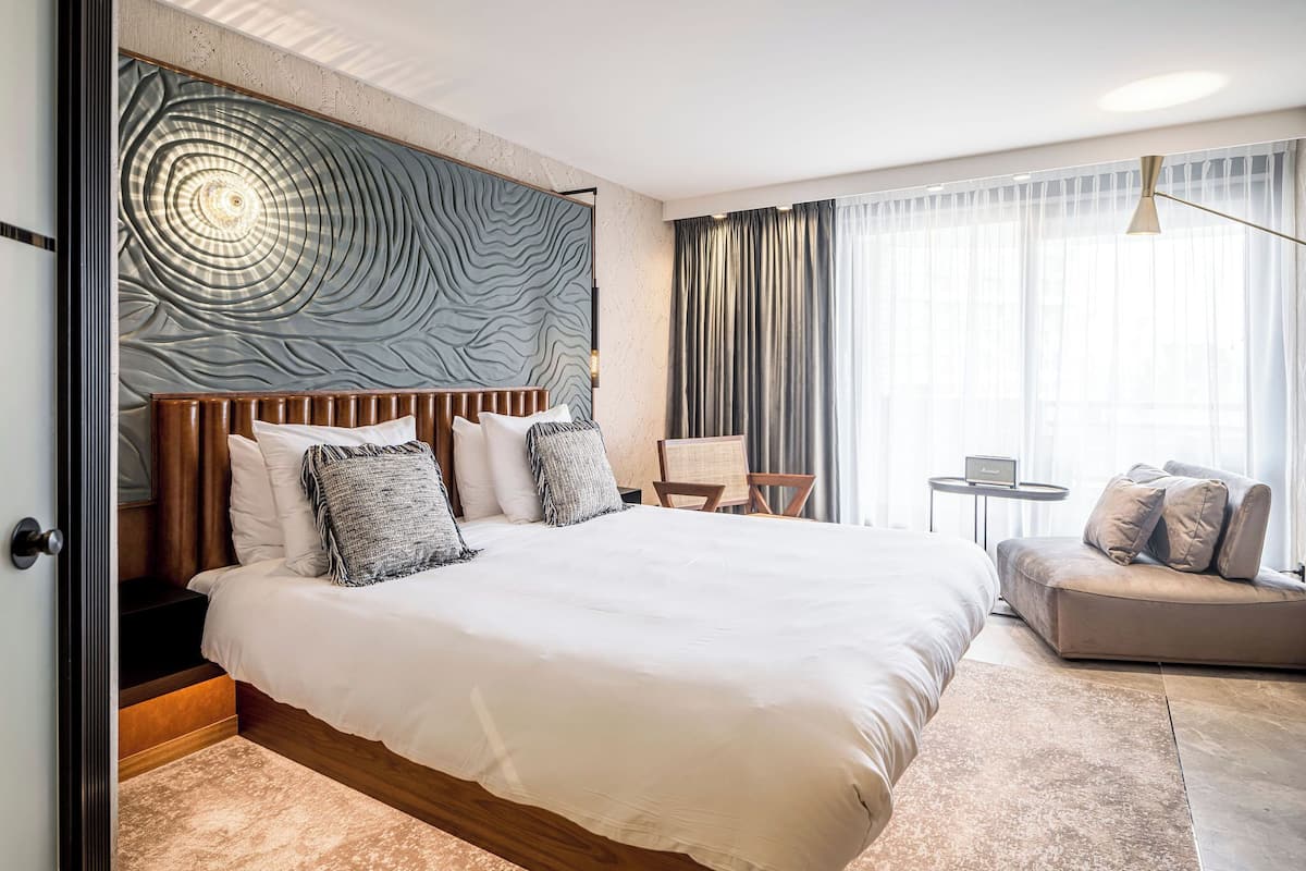 Une chambre d’hôtel moderne dotée d’un grand lit, d’un canapé, d’un bureau et d’un panneau décoratif mural.