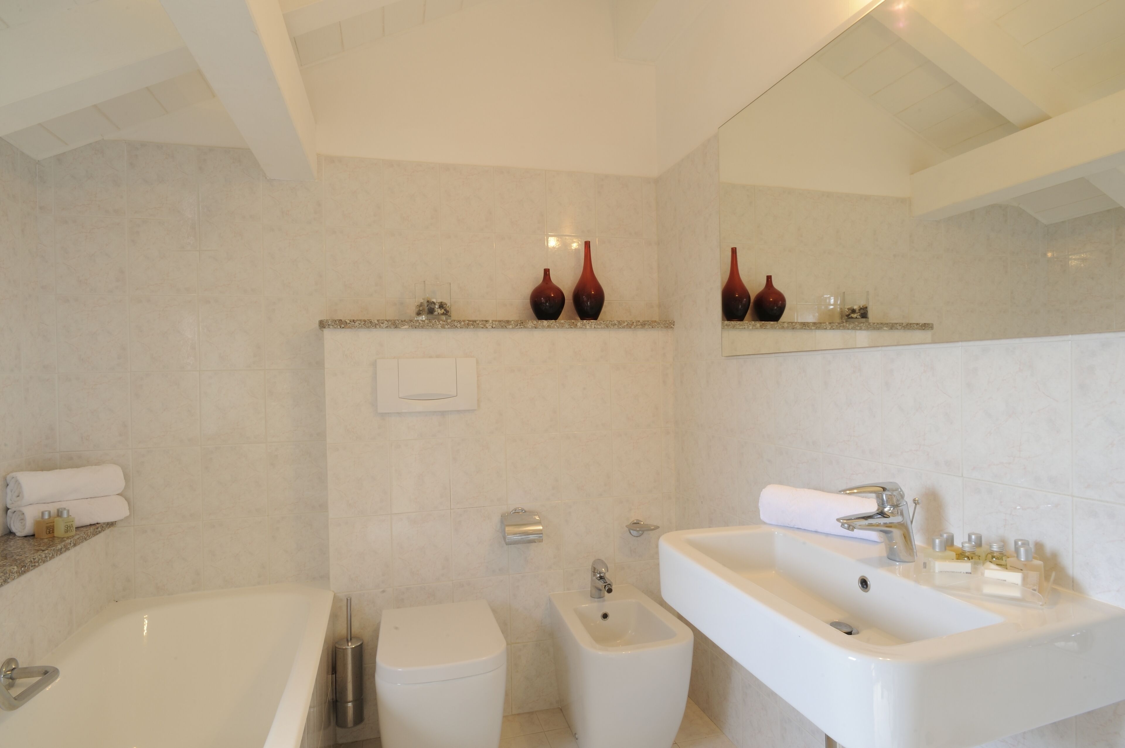 Een moderne badkamer met een badkuip, een hygiëneslot, een wastafel en een spiegel.
