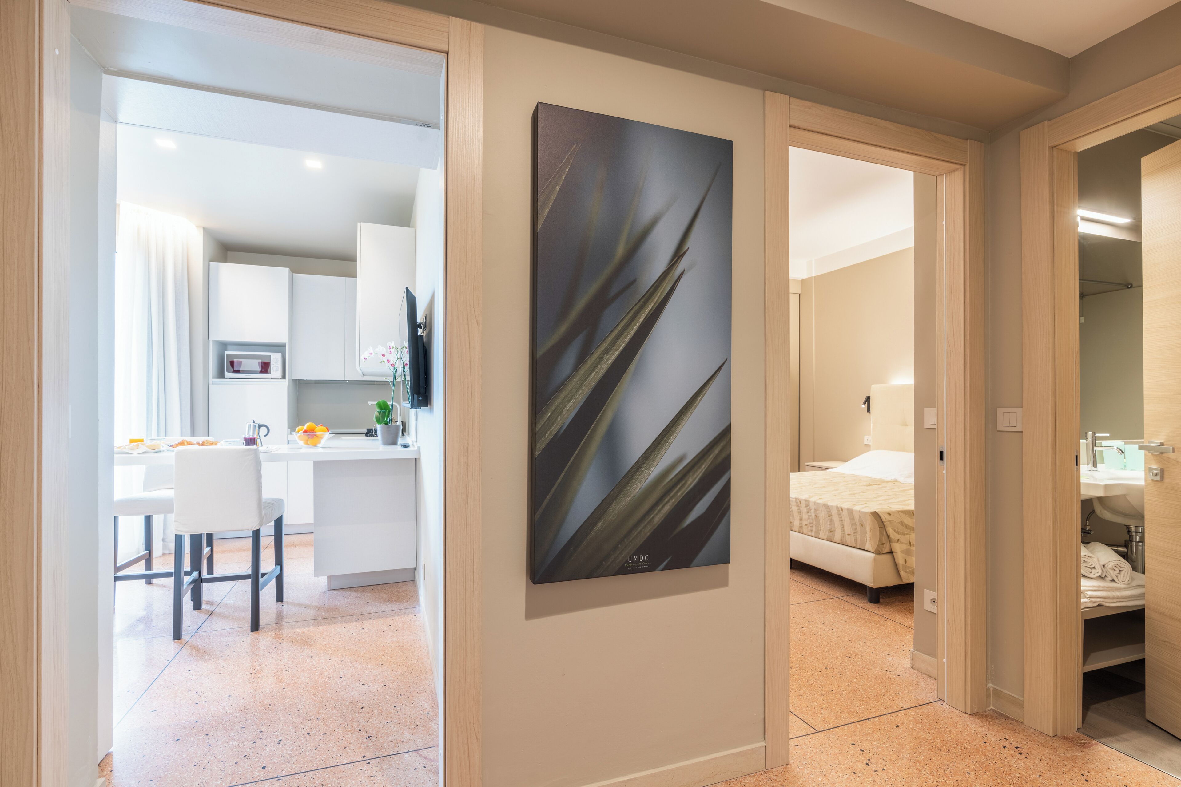 Quarto de hotel moderno com cama, banheiro e cozinha compacta.