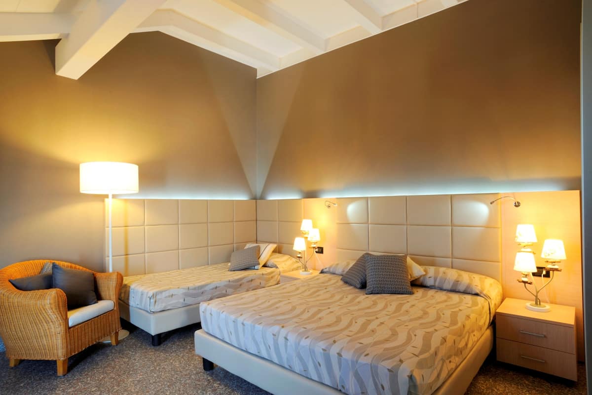 Ett hotellrum med två sängar, en stol och sängbord med lampor.