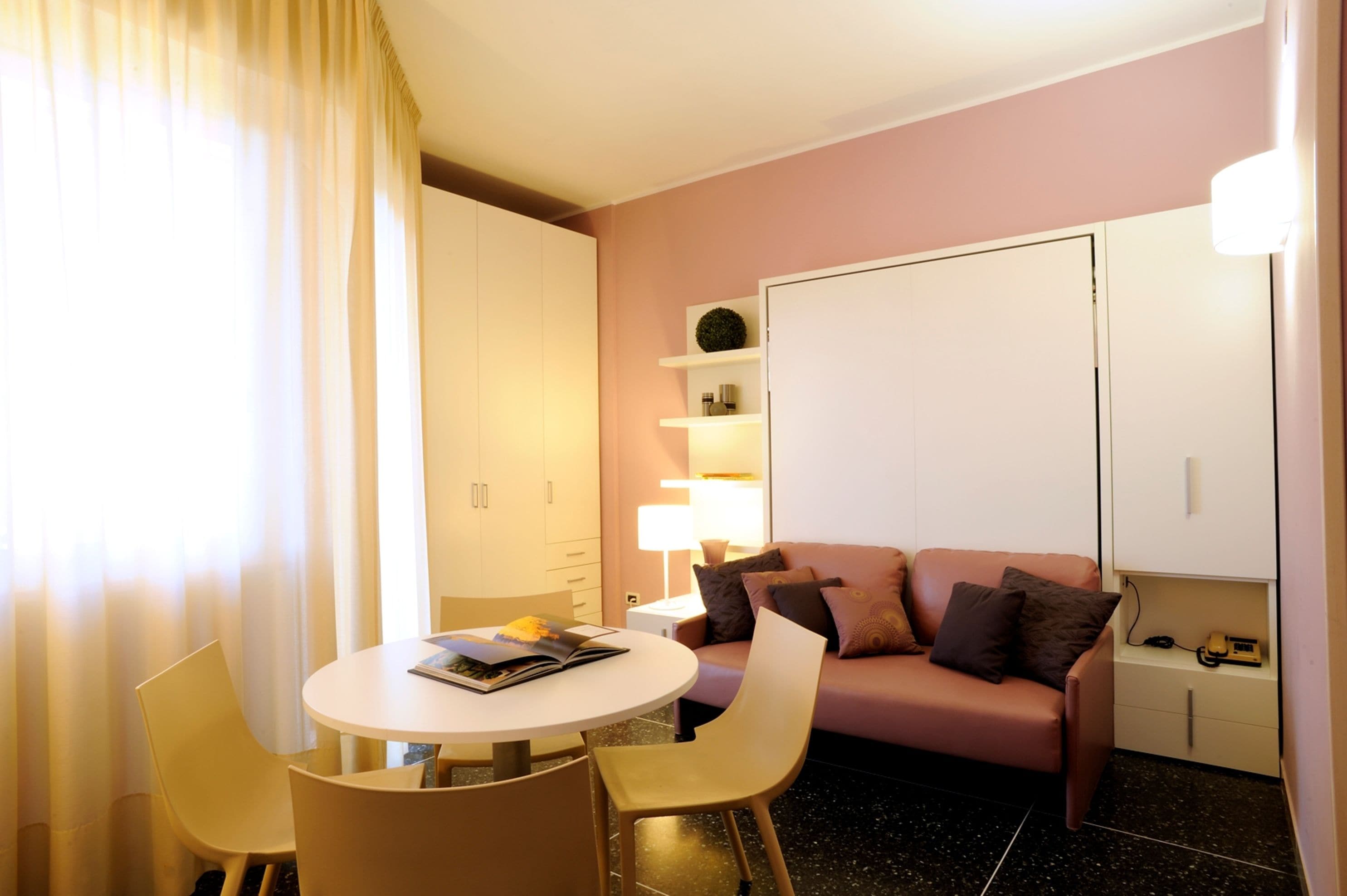 Une chambre d’hôtel de taille réduite, comprenant une table de salle à manger ronde, un canapé et un lit.