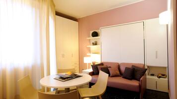 Une chambre d’hôtel de taille réduite, comprenant une table de salle à manger ronde, un canapé et un lit.
