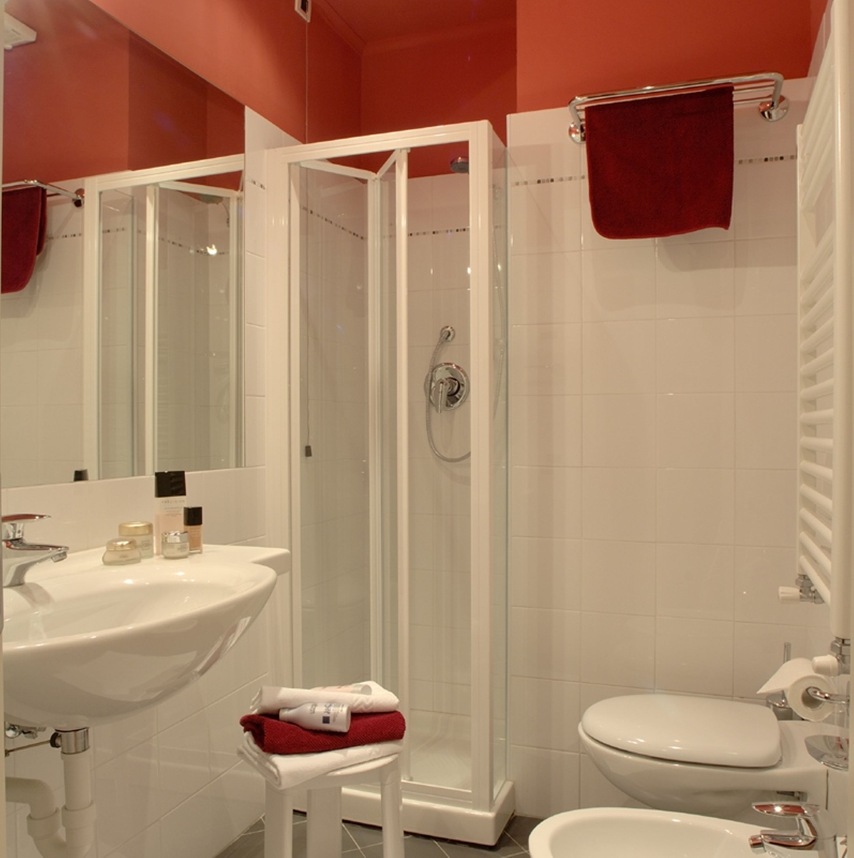 A bathroom with a white sink, a toilet, a glass-enclosed shower, and a mirror.