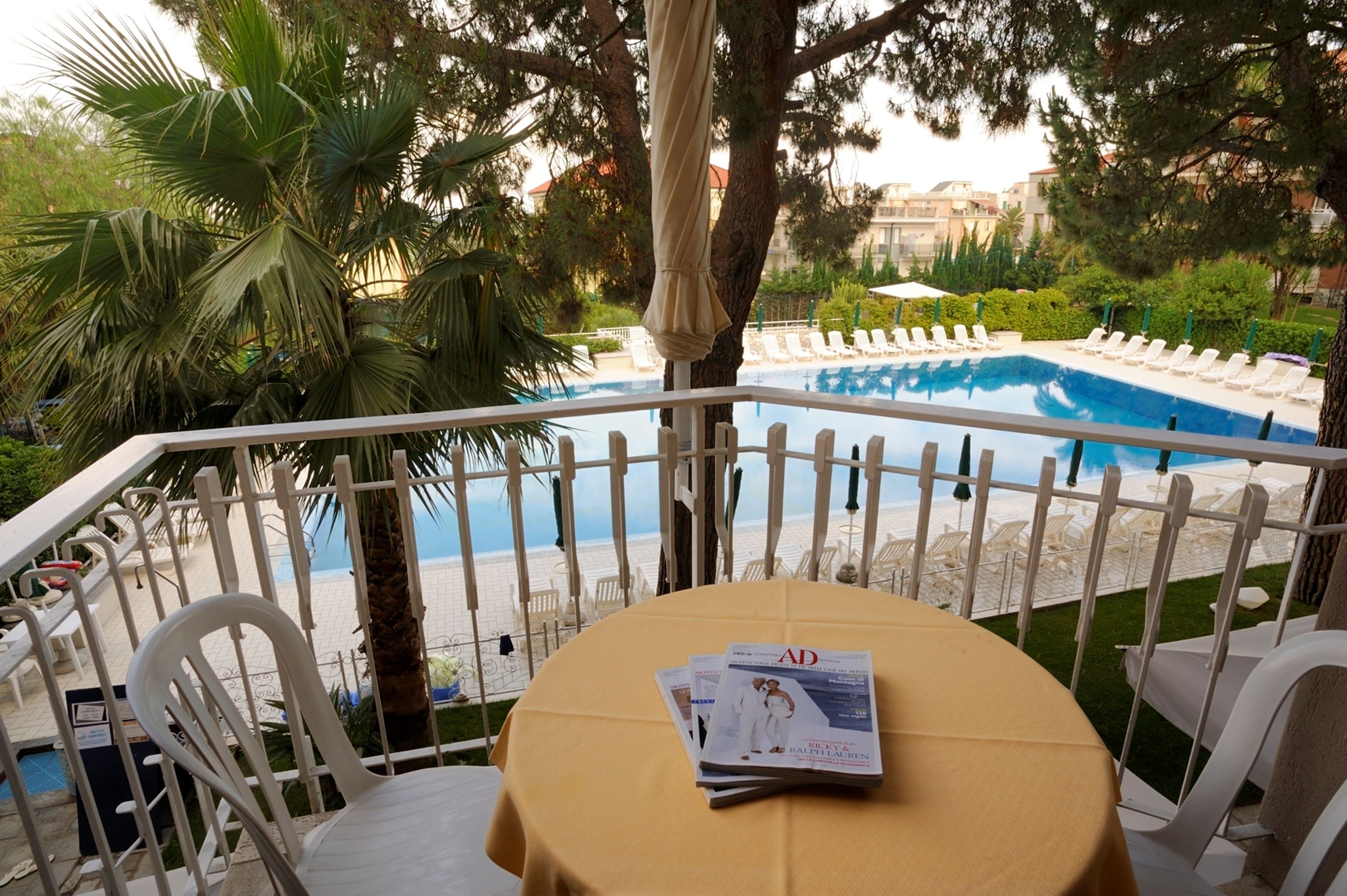 Un espace aménagé au bord de la piscine, avec une table recouverte d’une nappe jaune, des chaises longues blanches et une vue sur la piscine et la plage.