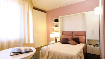 A hotel room with a bed, bedside table, lamp, and a chair.