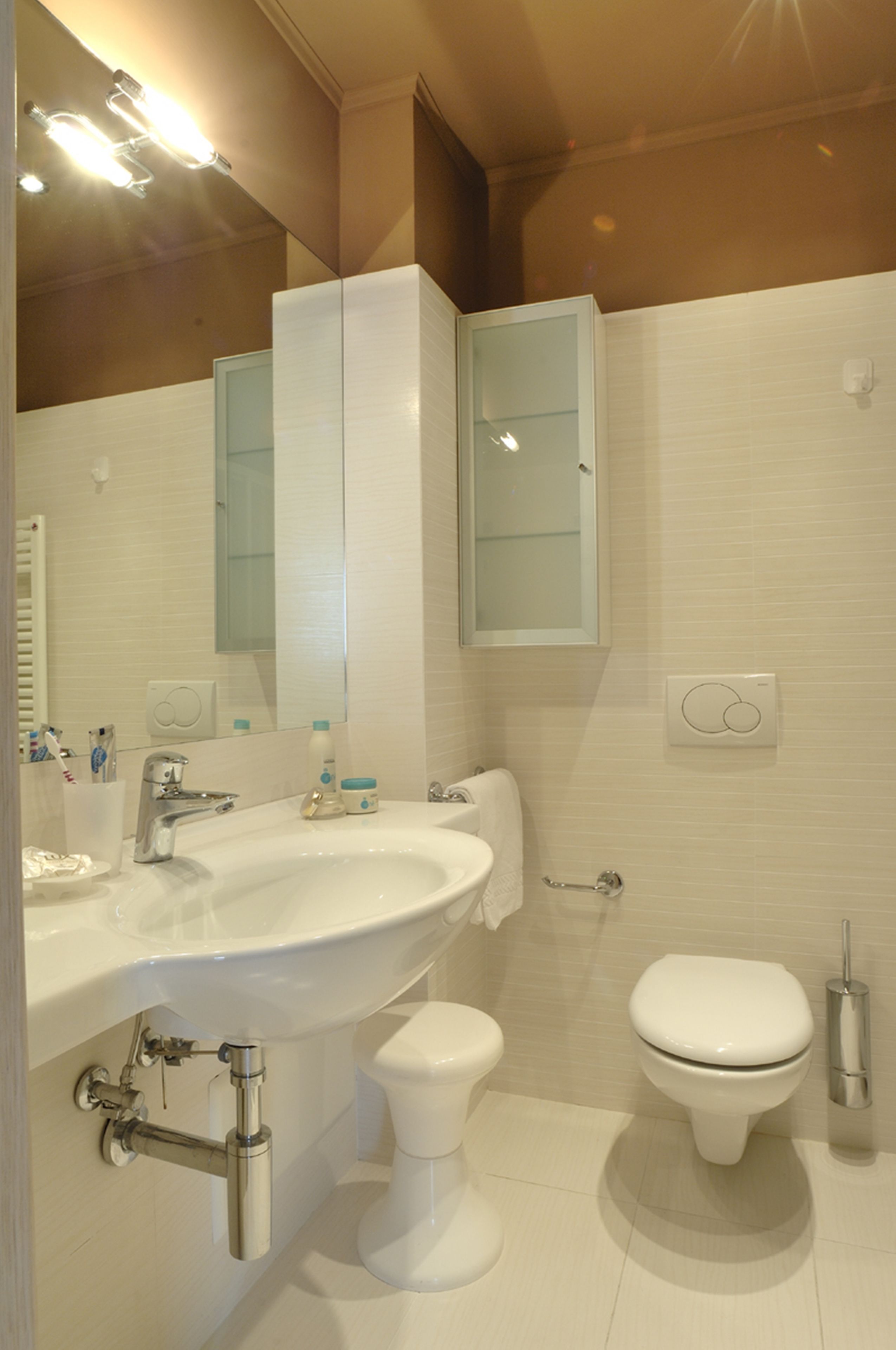 A modern bathroom with a white sink, mirror, and toilet.